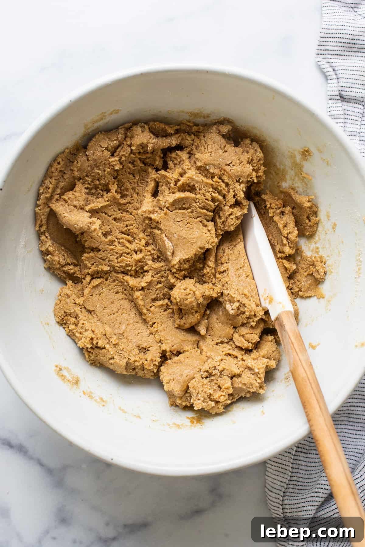 Peanut Butter Twix Cups Recipe — Homemade Candy Bars in Minutes 4 Peanut butter cookie dough in a bowl with a wooden spoon.