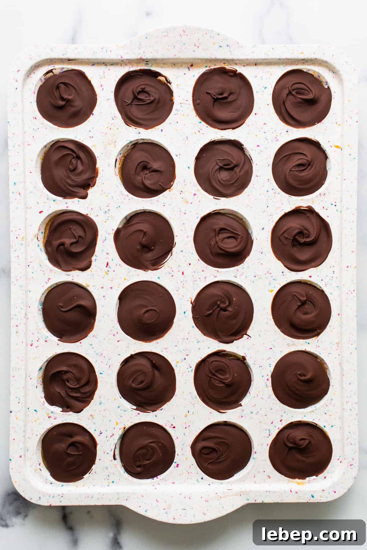 Peanut Butter Twix Cups Recipe — Homemade Candy Bars in Minutes 5 A tray of chocolate dipped cupcakes on a marble countertop.