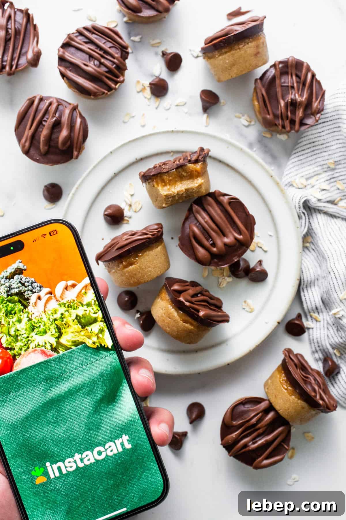 Peanut Butter Twix Cups Recipe — Homemade Candy Bars in Minutes 6 A person holding a smartphone with a plate of cookies and brownies.