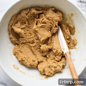 Peanut Butter Twix Cups Recipe — Homemade Candy Bars in Minutes 9 Peanut butter cookie dough in a bowl with a wooden spoon.