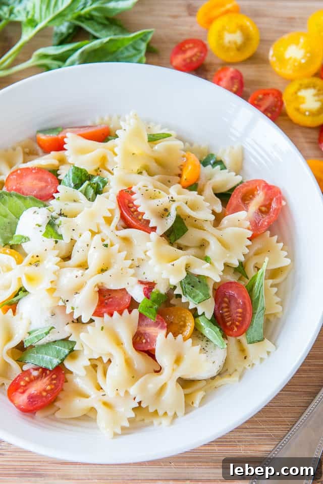 20+ Picnic and Potluck Salads That Stay Fresh and Travel Well 8 Caprese Pasta Salad - in White Bowl with Fresh Basil and Grape Tomatoes