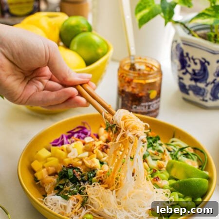 Spring Roll Bowl Recipe: Fresh Vietnamese Salad Bowl with Dipping Sauce 11 a bowl of spring roll ingredients that someone is taking a bite out of with chopsticks