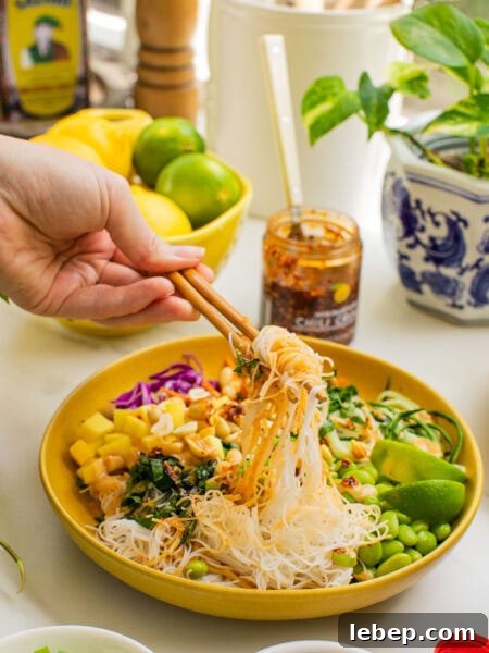 Spring Roll Bowl Recipe: Fresh Vietnamese Salad Bowl with Dipping Sauce 10 a bowl of spring roll ingredients that someone is taking a bite out of with chopsticks