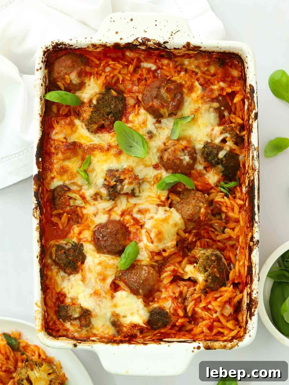 An oven dish filled with cooked Meatball Orzo Bake, straight out of the oven, topped with cheese and ready to serve.