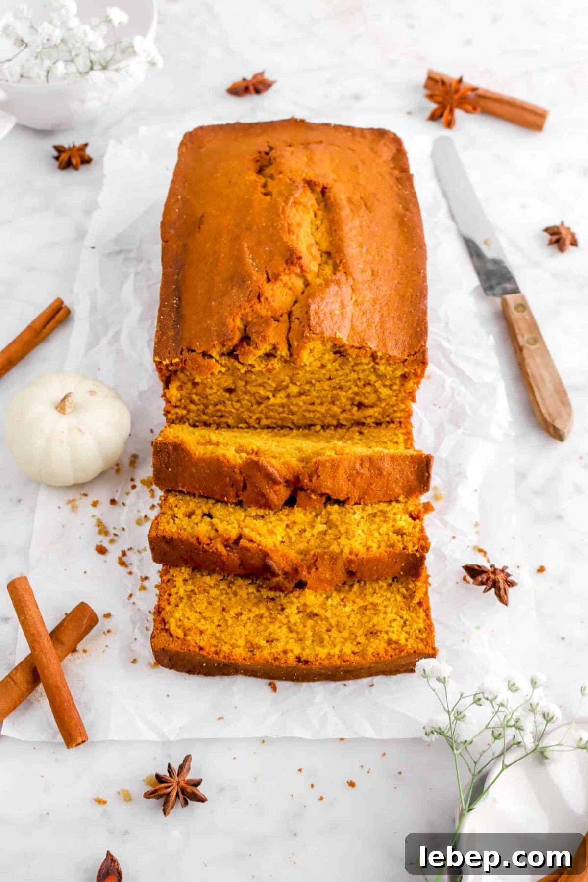 Moist Pumpkin Bread Recipe with Warm Spices 17 three slices of pumpkin bread on parchment in front of loaf