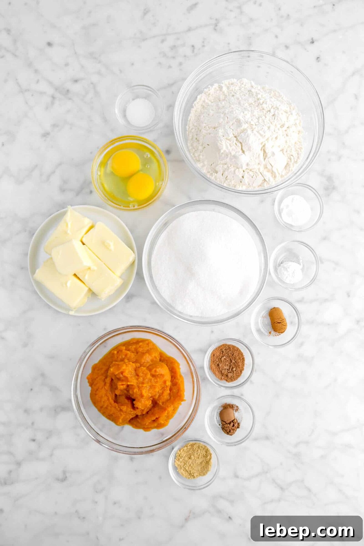 Moist Pumpkin Bread Recipe with Warm Spices 6 salt, flour, eggs, butter, sugar, baking soda, baking powder, cinnamon, nutmeg, cloves, ginger, and pumpkin puree on marble counter