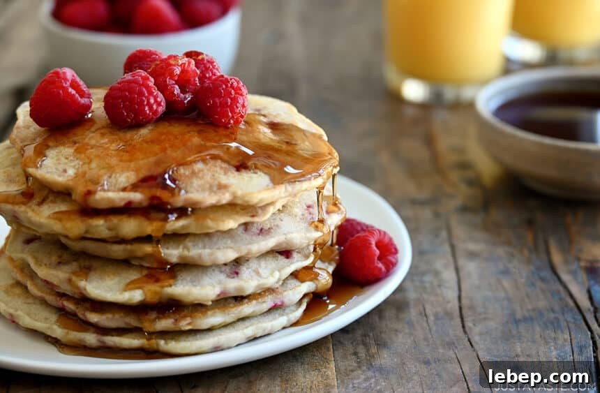 Fluffy Raspberry Oat Pancakes with Maple Glaze 5 A tall stack of Raspberry Oatmeal Pancakes topped with fresh raspberries and drizzled with maple syrup