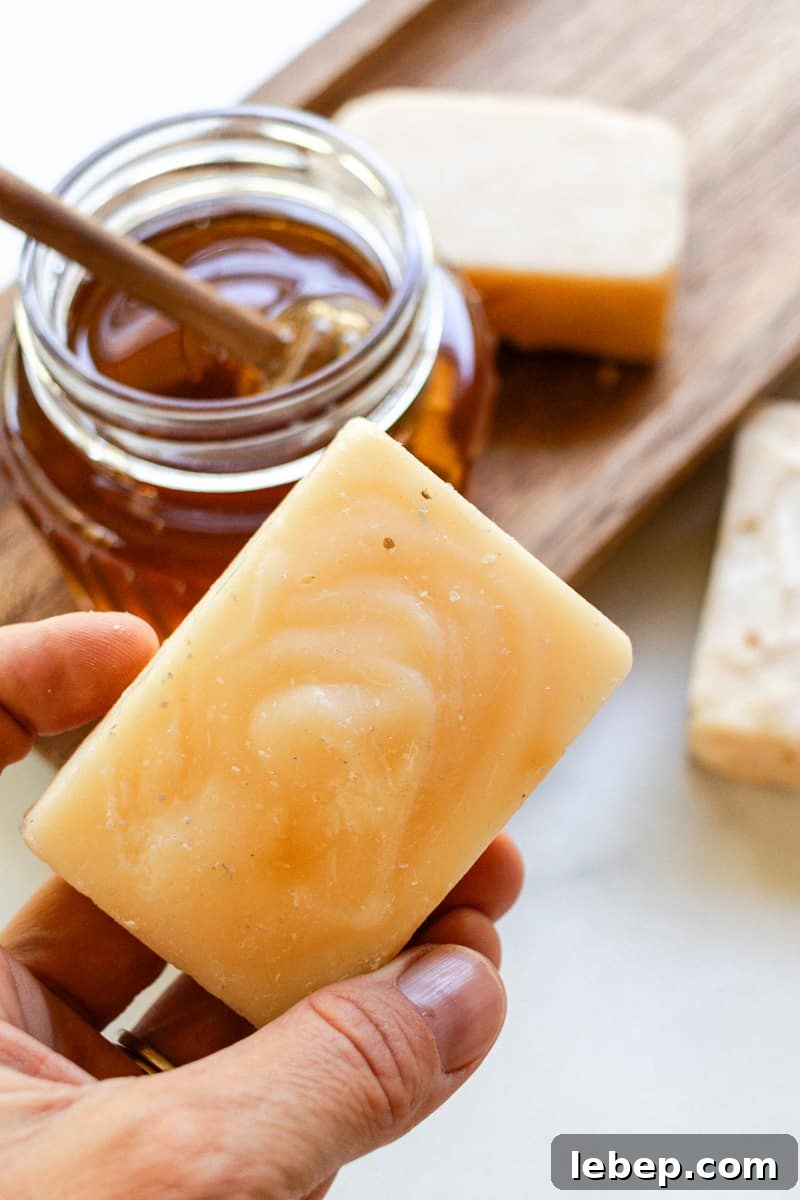 Holding a bar of honey soap with a glass of honey in the background.