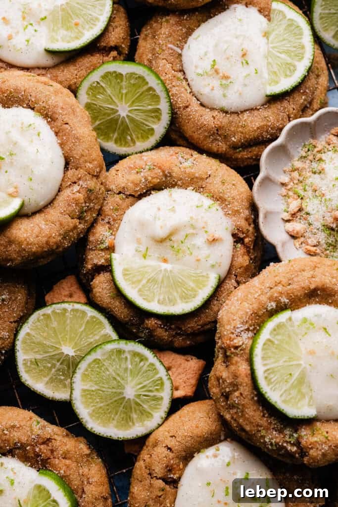 Key Lime Pie Cookies with Make-Ahead Prep Tips 2 Key lime pie cookies nestled together on a cooling rack, with slices of lime garnishing the cookies.