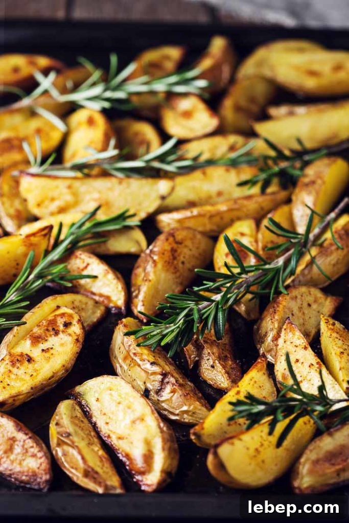 Baked Potato Wedges with fresh rosemary on a sheet pan