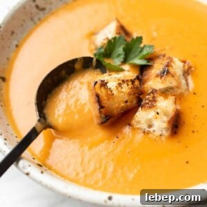 Creamy Potato, Leek & Tomato Soup Recipe for Cozy Meals 7 a bowl of potato leek tomato soup with croutons and a spoon