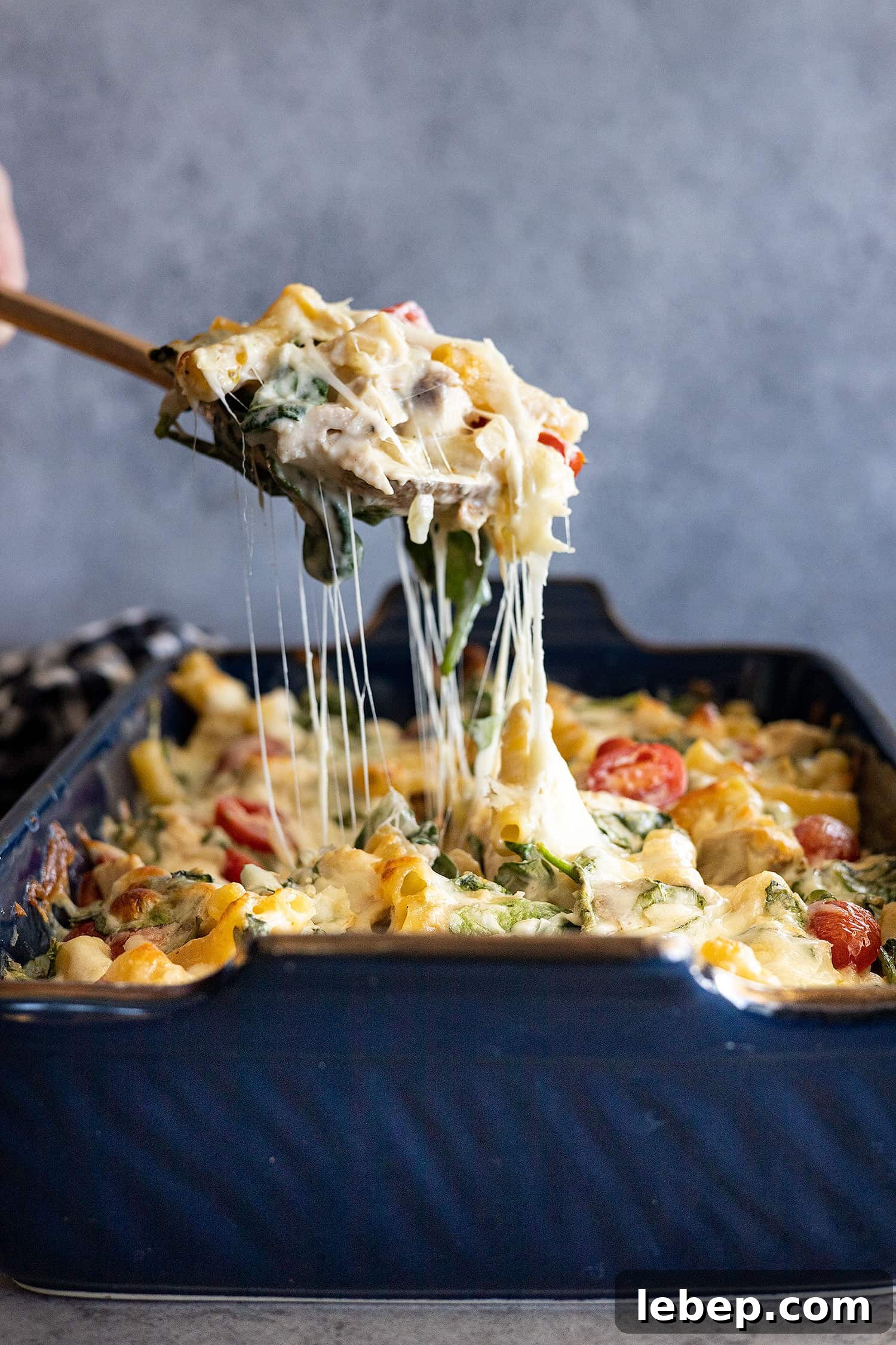 Creamy Chicken Florentine Pasta Bake Recipe 6 Spoon pulling up the casserole showing a nice cheese pull.