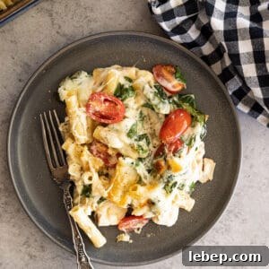 Creamy Chicken Florentine Pasta Bake Recipe 7 Overhead of casserole on a dark plate with fork off to the side.