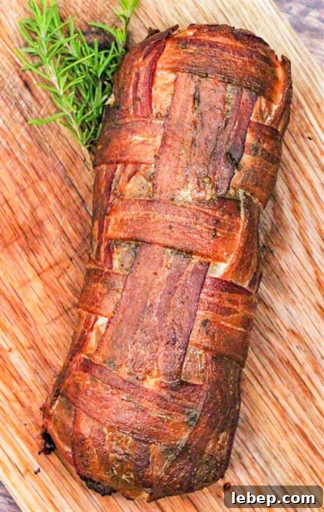 smoked bacon wrapped turkey breast on a wood cutting board with a sprig of rosemary