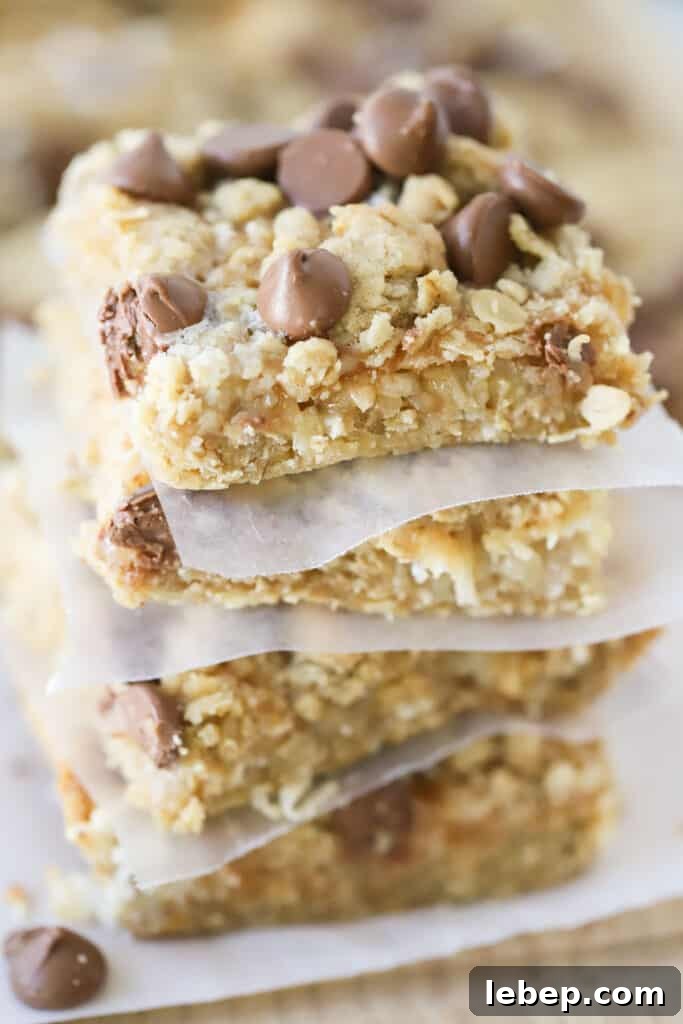 A stack of seven layer magic cookie bars topped with chocolate chips.