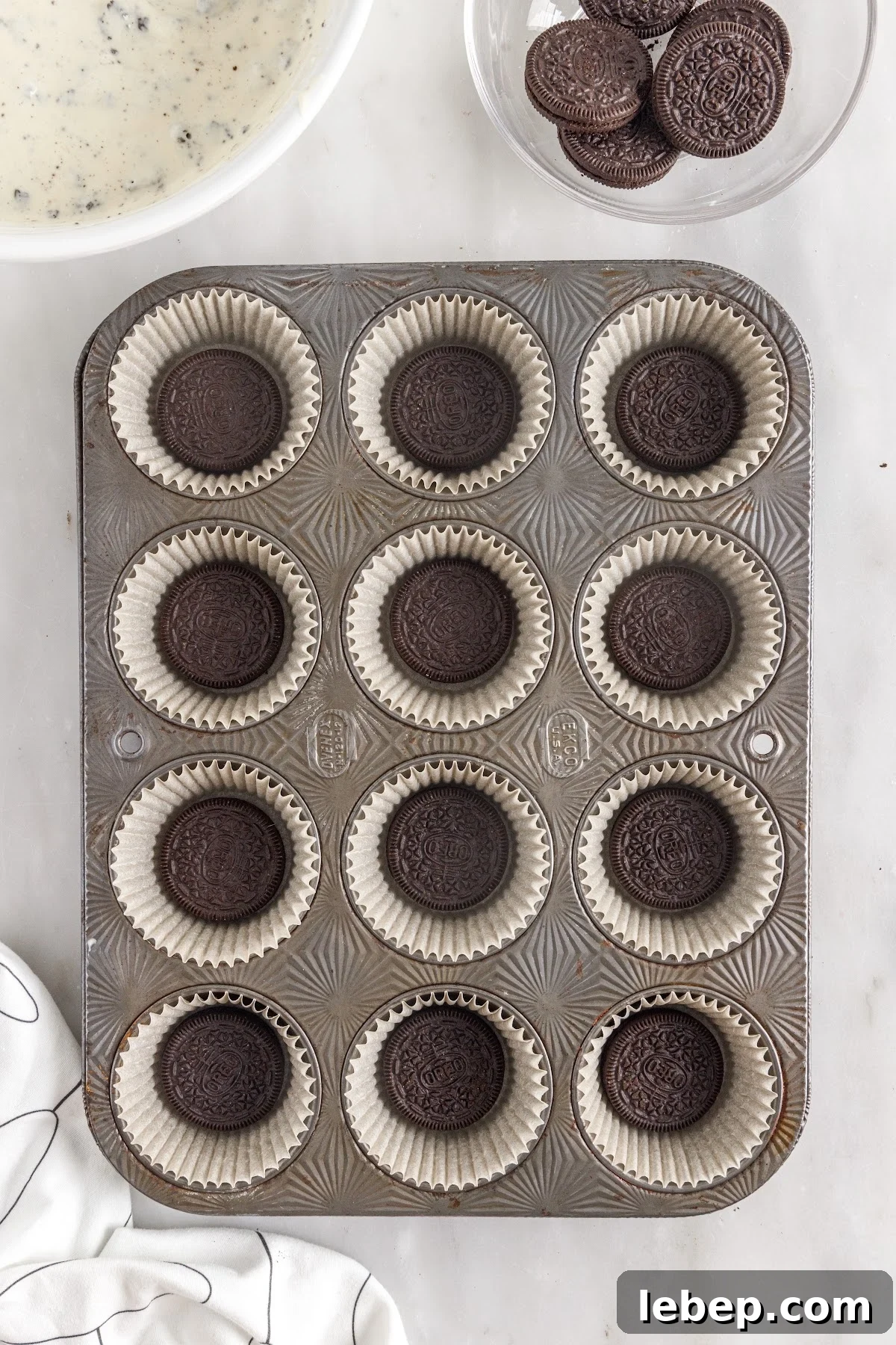 Muffin Pan lined with cupcake liners and an Oreo in the center of each one.
