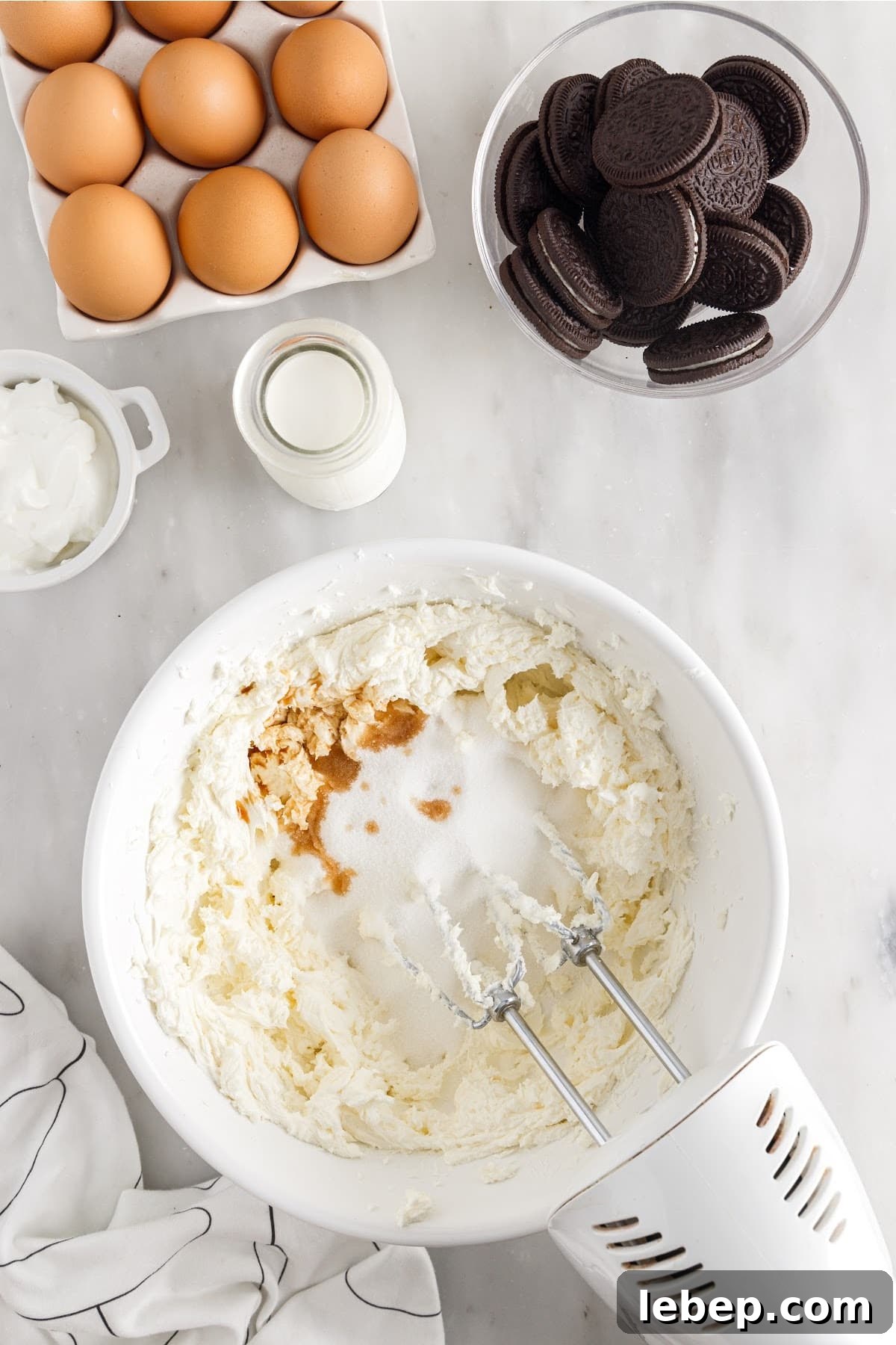 Cheesecake ingredients being mixed with a hand mixer.