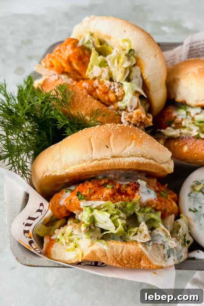 assembled buffalo chicken sandwiches beside sprigs of fresh dill on newspaper.