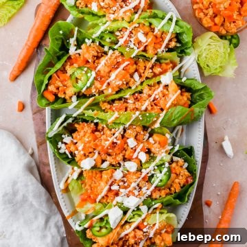 loaded buffalo cauliflower chicken lettuce wraps garnished with ranch and feta on white serving plate.