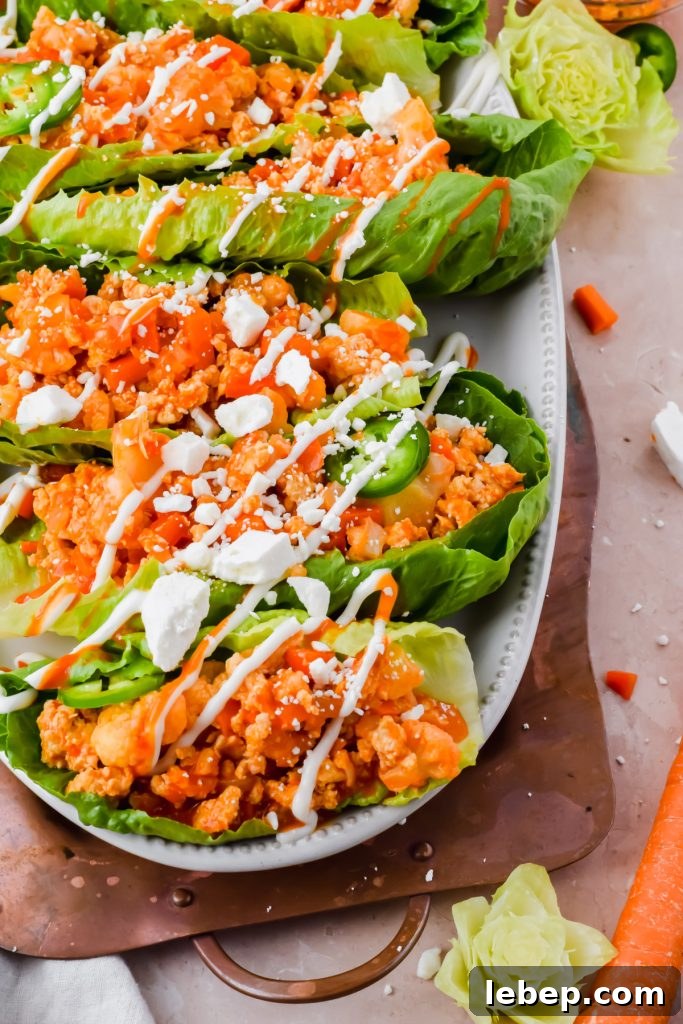 loaded buffalo cauliflower chicken lettuce wraps garnished with ranch and feta on white serving plate.