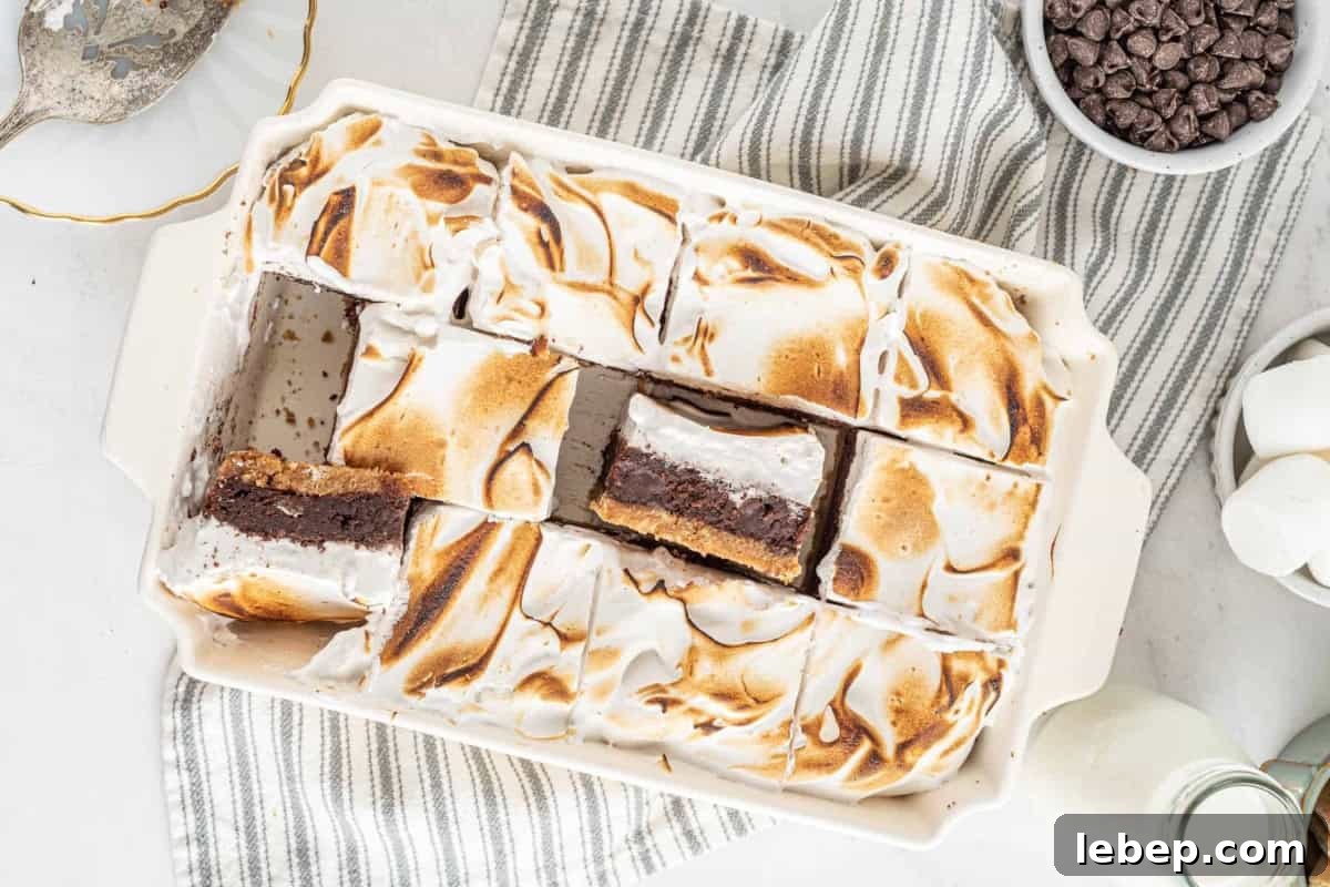 S'mores Brownies Recipe: Gooey Chocolate Graham Bars 3 cut s'mores brownies in a baking pan, some are turned up to show the layers.