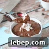 Dairy-free chocolate pudding in a white ramekin with coconut whip cream on top.
