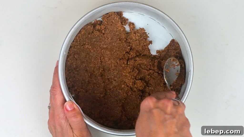 pressing cookie crumb crust into cake tin