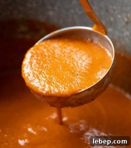 close up shot of ladle scooping up soup out of large pot