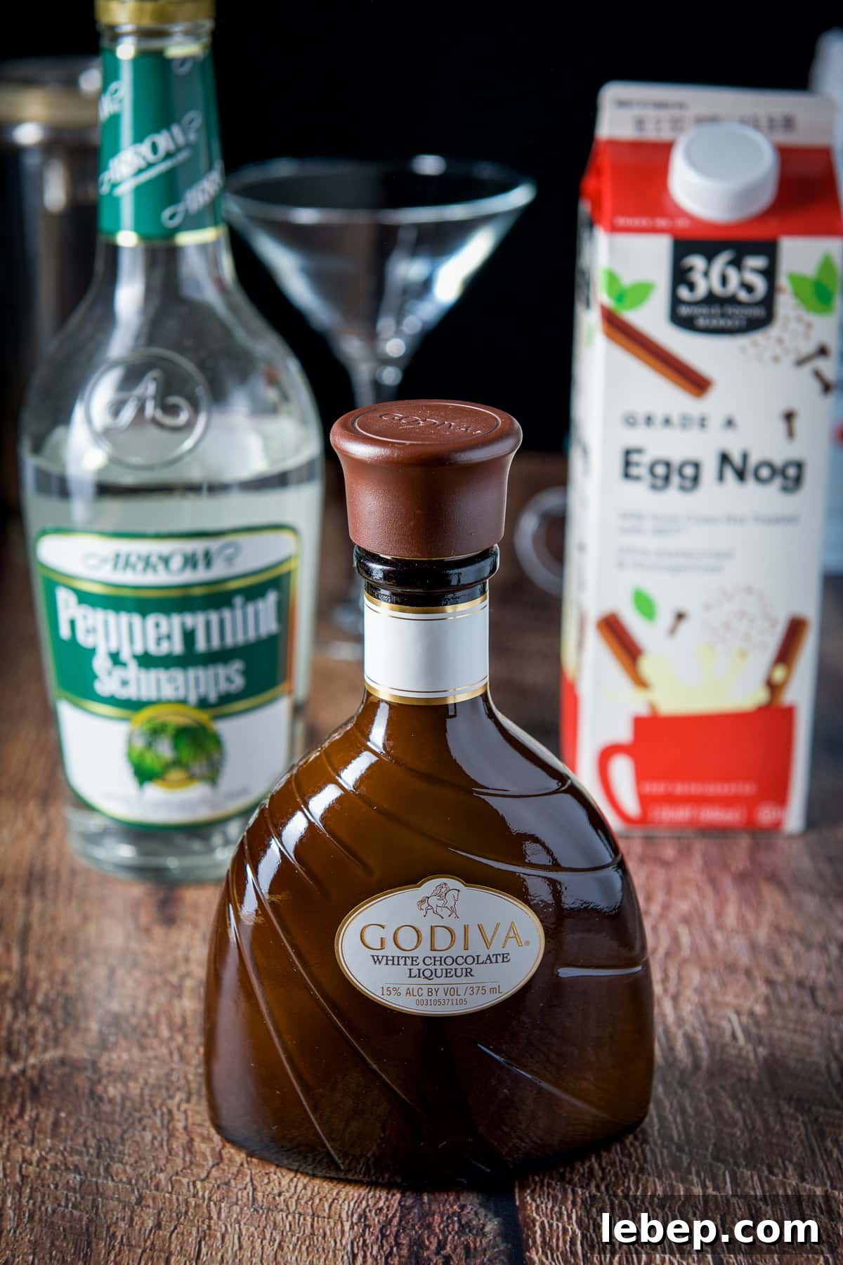 Mrs. Claus Cocktail Recipe: Festive Spiced Holiday Drink 3 White chocolate liqueur, egg nog and peppermint schnapps on a wood table