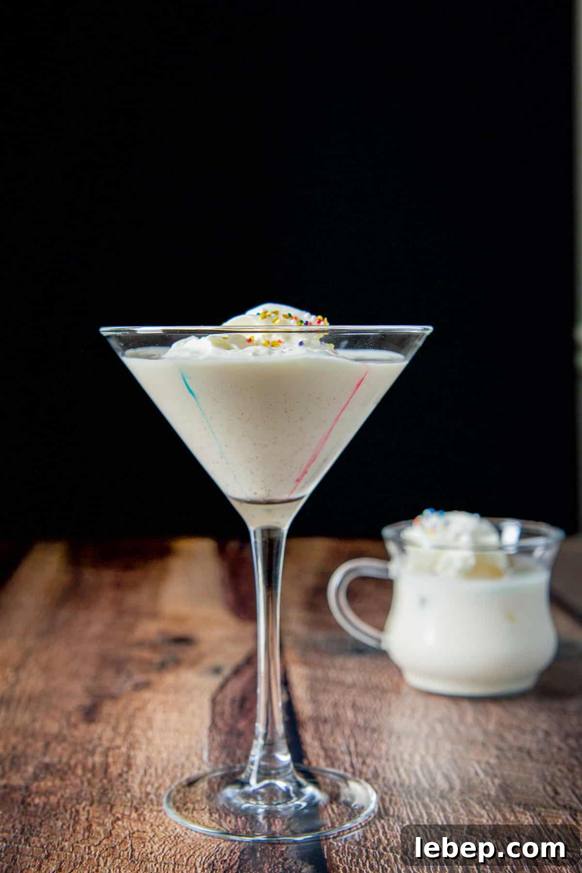 Mrs. Claus Cocktail Recipe: Festive Spiced Holiday Drink 8 Vertical view of the classic martini glass filled with the egg nog cocktail with colored streaks down the side