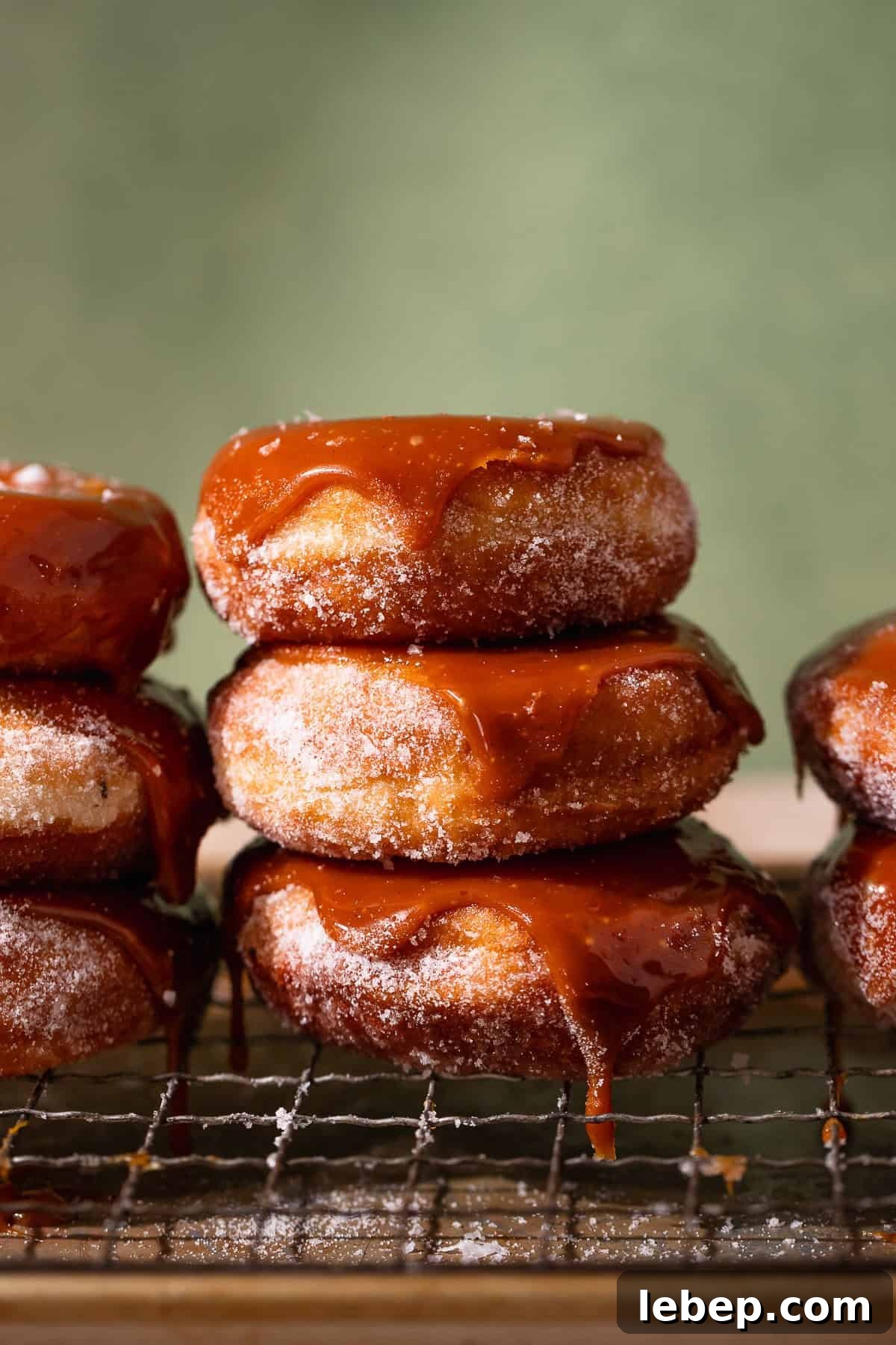Salted Caramel Donuts with Shiny Caramel Glaze 11 Three caramel donuts stacked on top of each other dripping with caramel.