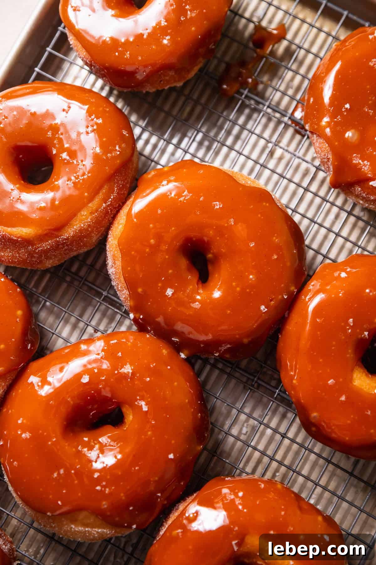 Salted Caramel Donuts with Shiny Caramel Glaze 10 A wire rack with salted caramel donuts on top.
