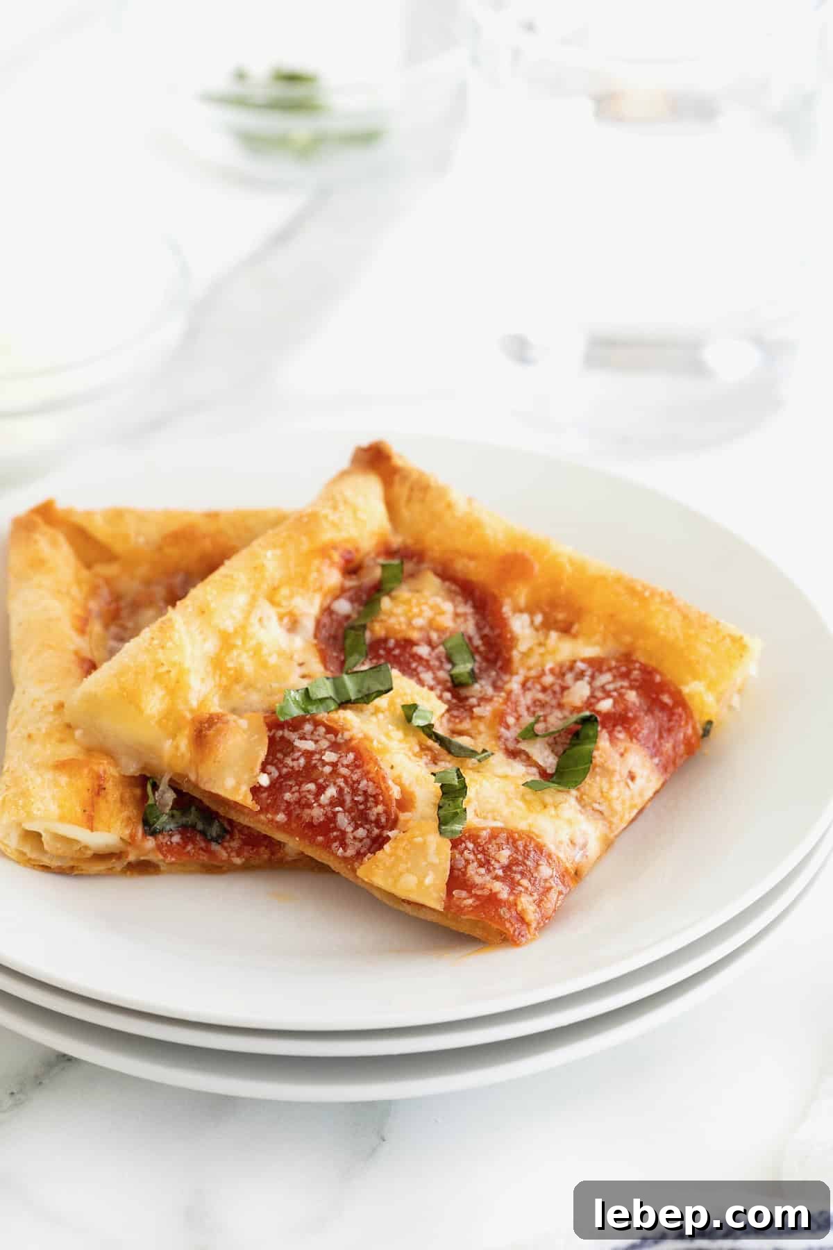 Two slices of stuffed crust tortilla pizza on a stack of three small white plates.