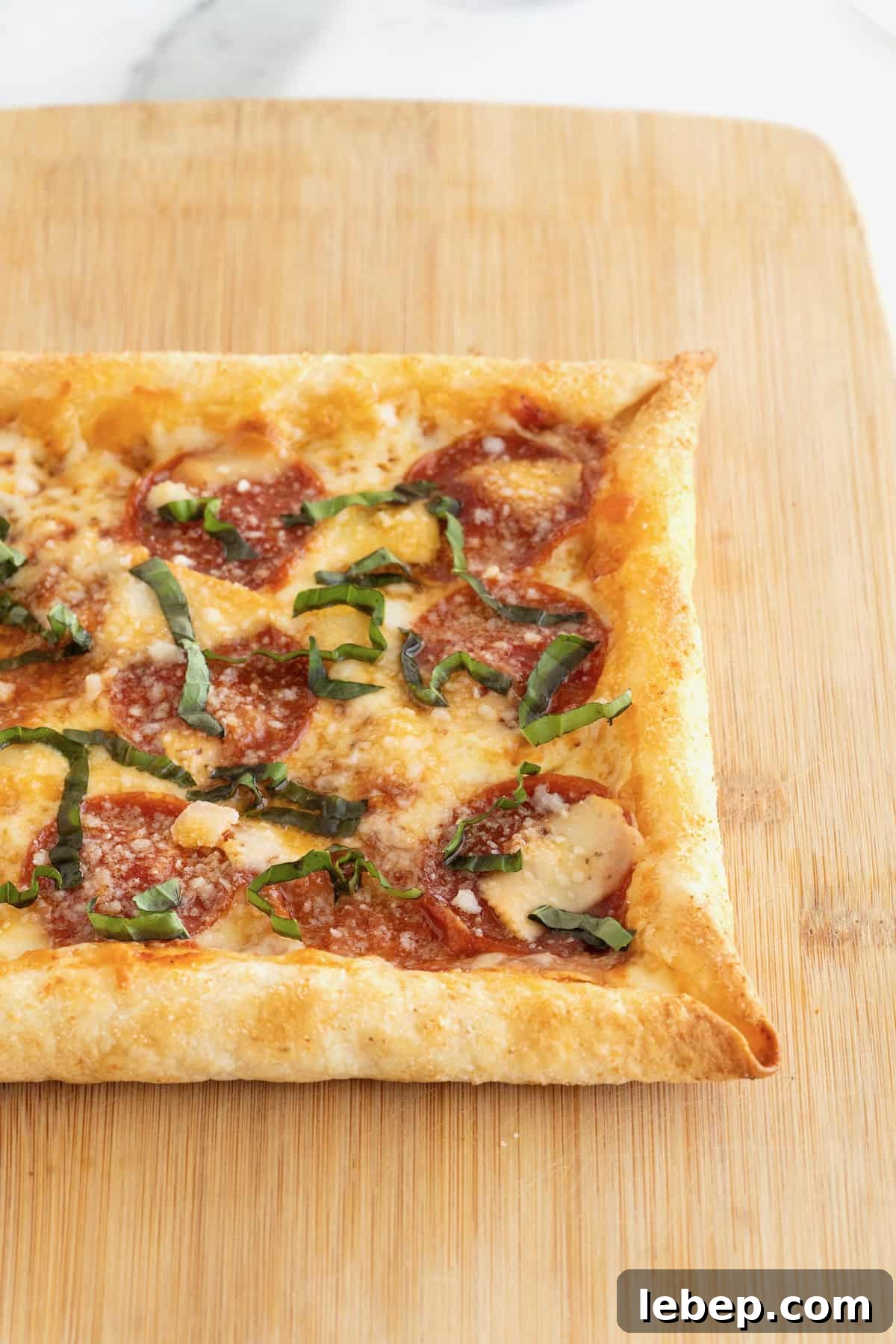 A stuffed crust tortilla pizza on a rectangular light wood cutting board.