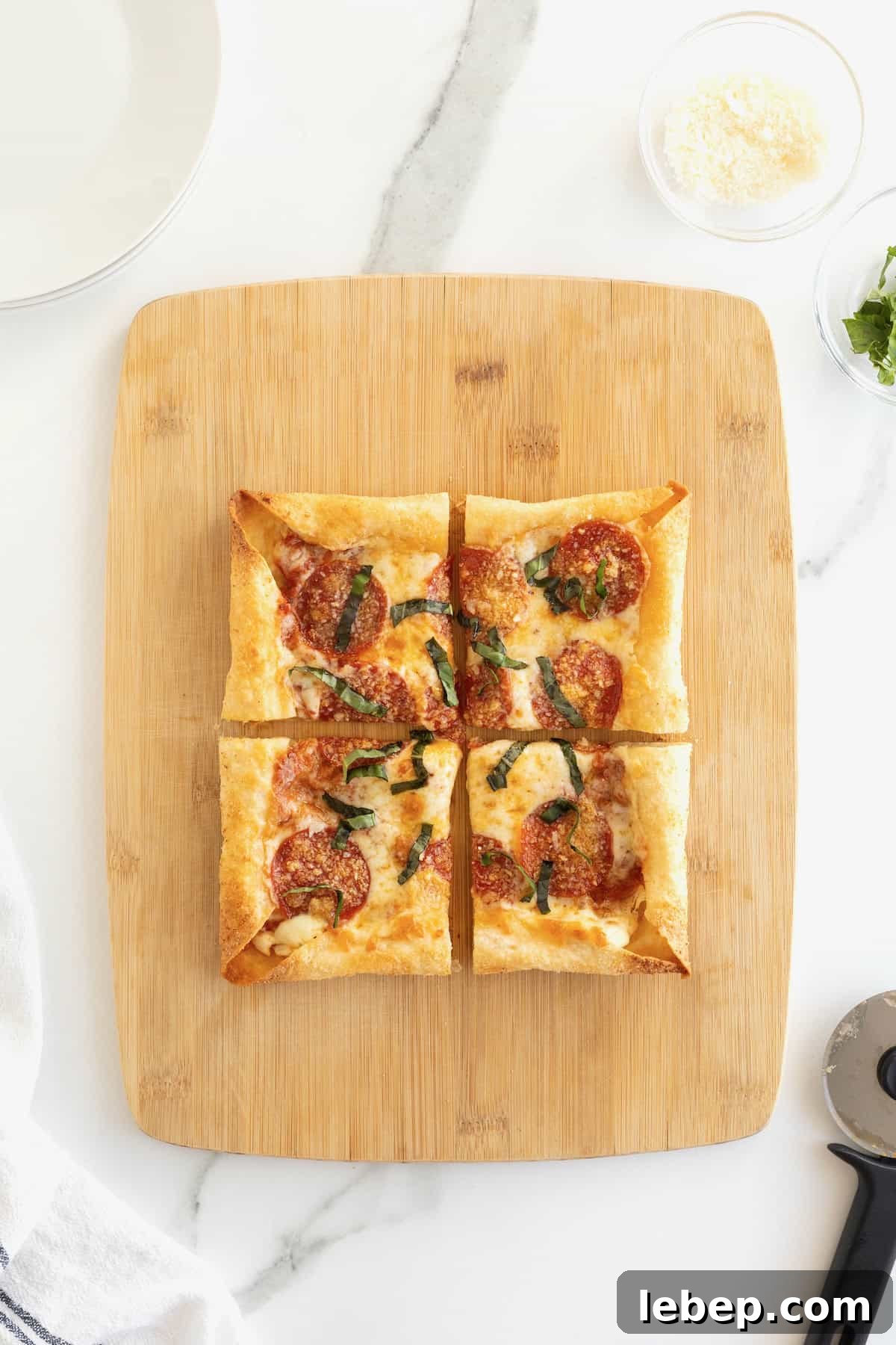 A stuffed crust tortilla pizza cut into four pieces on a rectangular light wood cutting board.