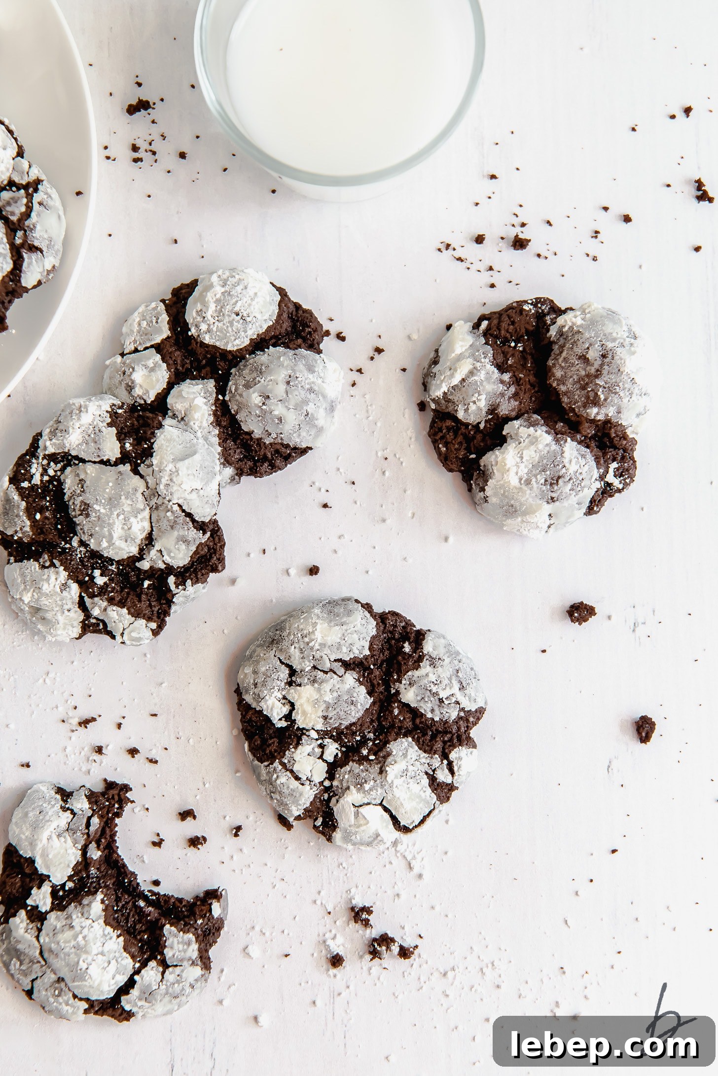 Chocolate Crinkle Cookies Recipe — Soft Fudgy Cookies in Minutes 6 chocolate crinkle cookies on a white surface next to glass of milk