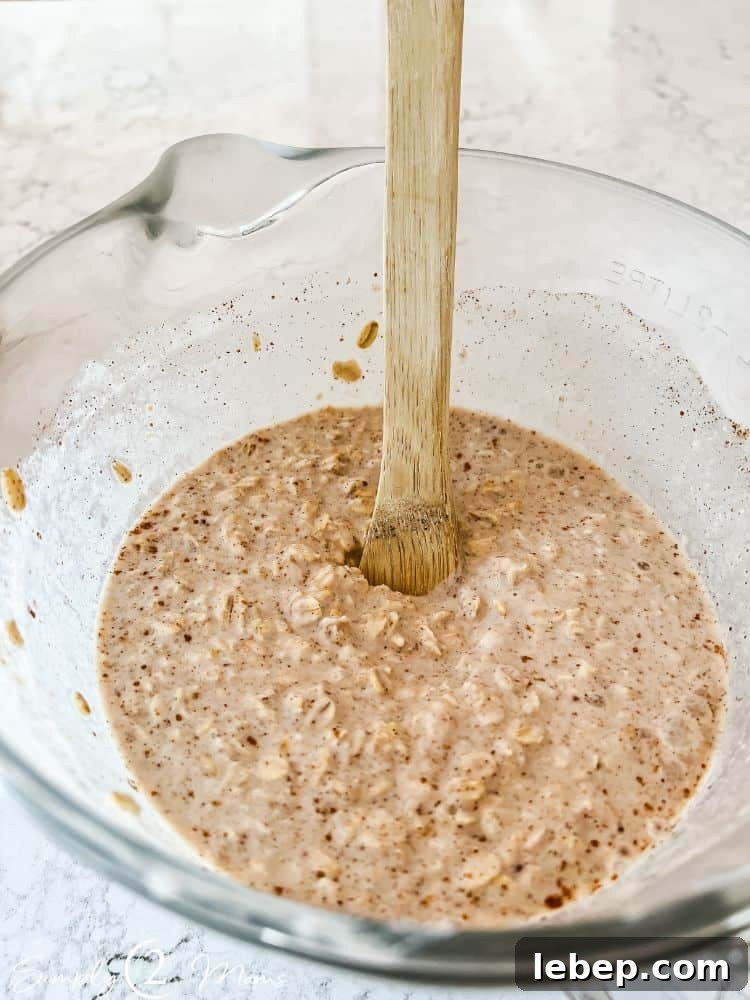 Peach Cobbler Overnight Oats (THM-E) — Make Ahead Recipe 5 Overnight oats mixture with Greek yogurt and cinnamon in a glass bowl with spout and handle.