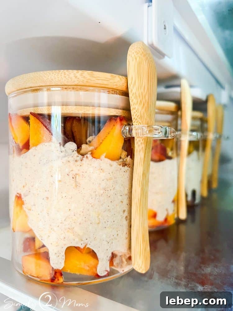 Peach Cobbler Overnight Oats (THM-E) — Make Ahead Recipe 8 THM Peach cobbler overnight oats with in glass jars with bamboo lids and attached bamboo spoons in the refrigerator.