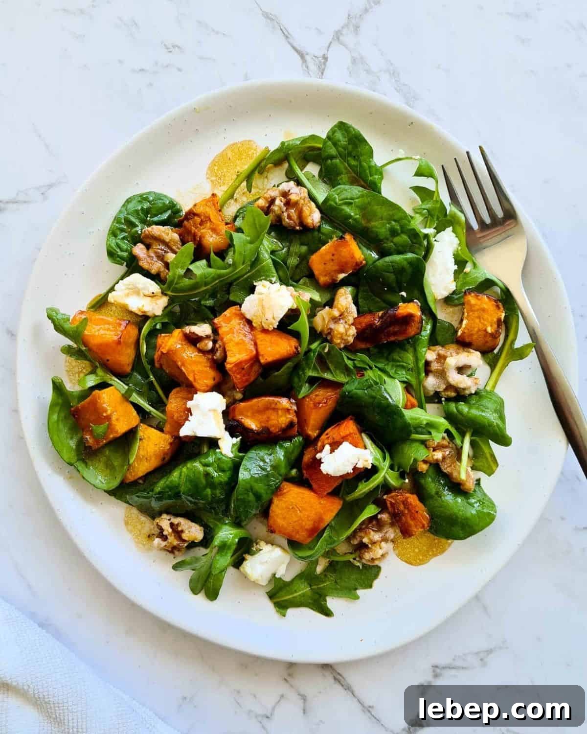 Roasted Pumpkin, Spinach & Goat Cheese Salad Recipe 7 Overhead view of salad on a white plate with a fork