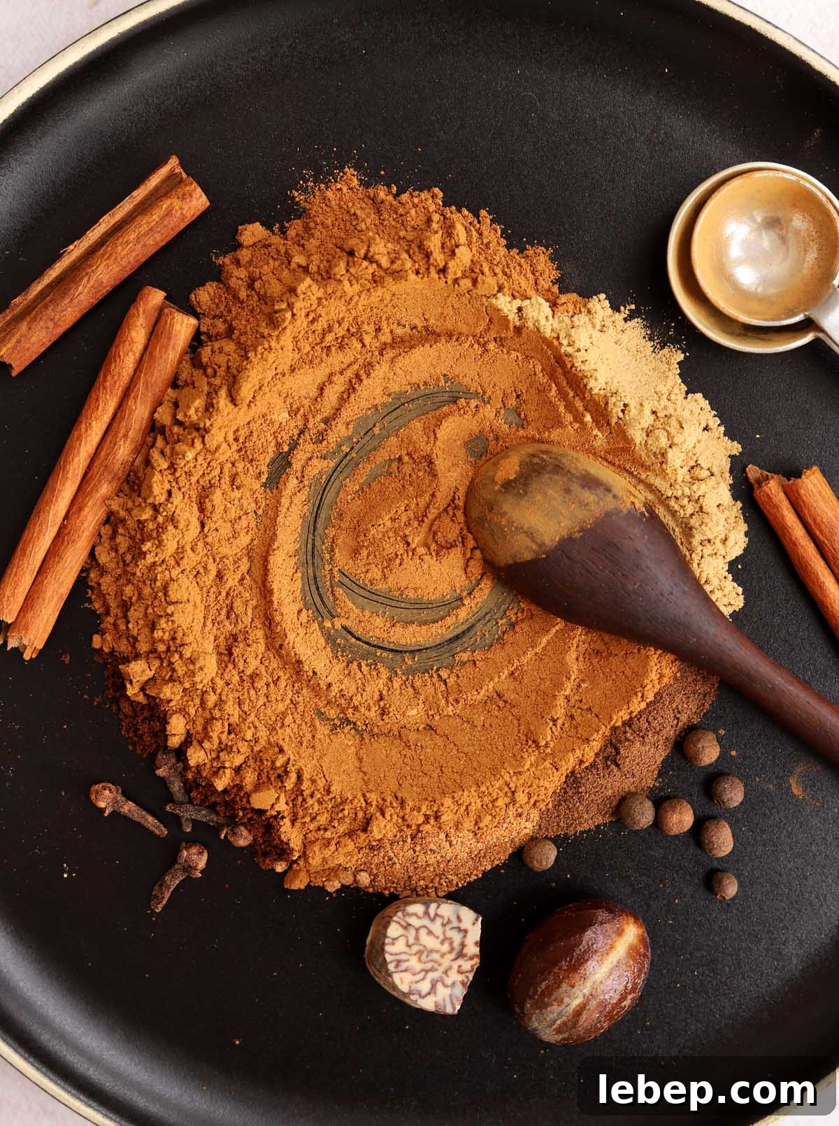 Homemade Pumpkin Pie Spice Blend for Baking & Lattes 2 homemade pumpkin pie spices on a black plate blending together with a spoon
