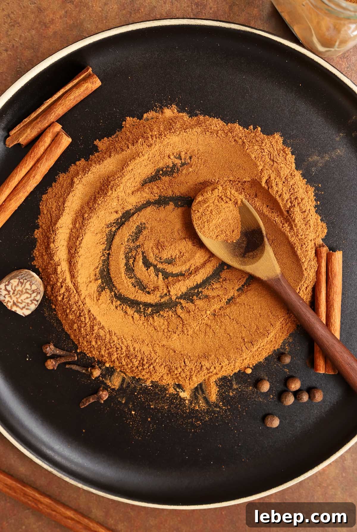 Homemade Pumpkin Pie Spice Blend for Baking & Lattes 6 homemade pumpkin pie spices on a black plate blending together with a spoon