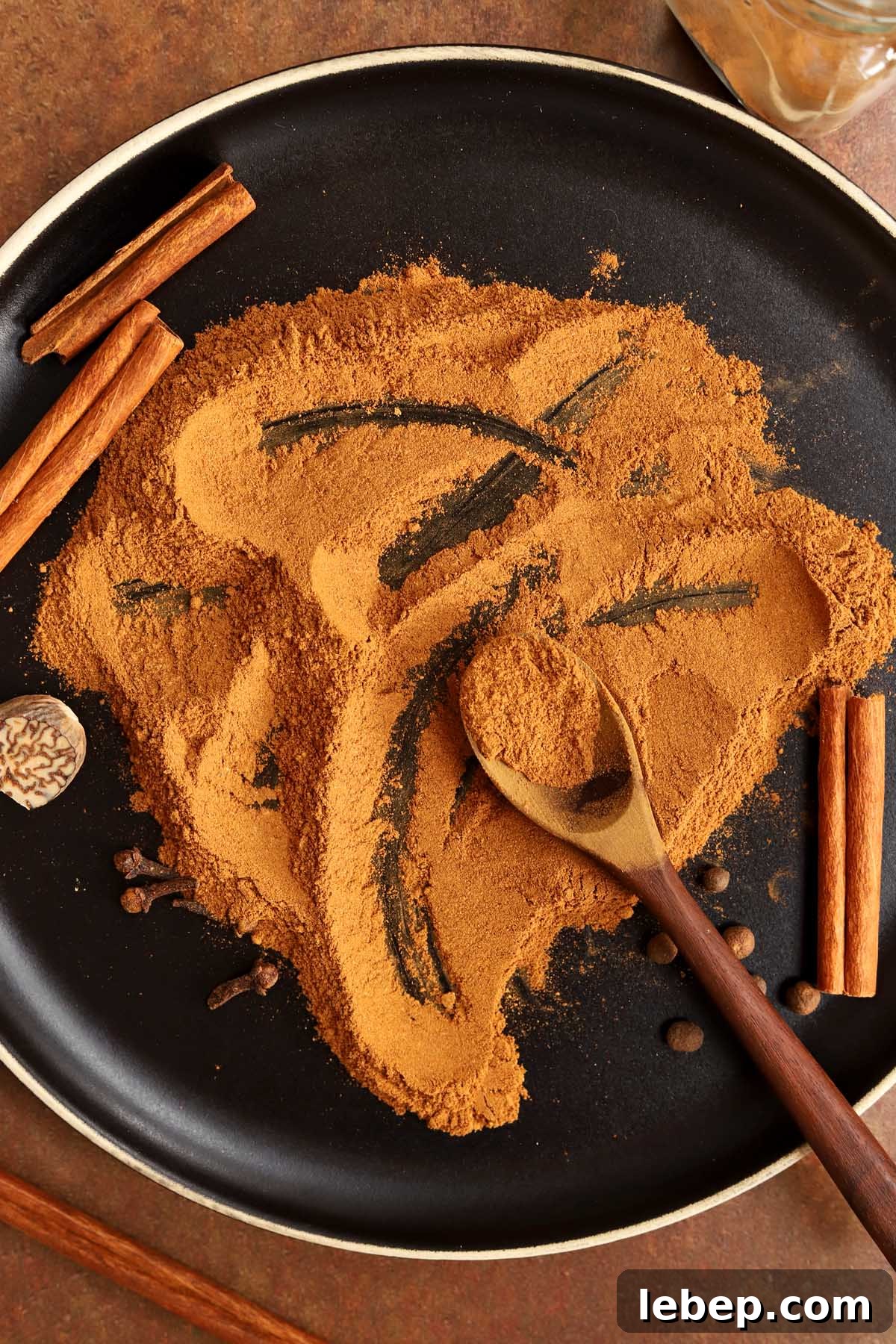 Homemade Pumpkin Pie Spice Blend for Baking & Lattes 7 homemade pumpkin pie spices on a black plate blended together with a spoon