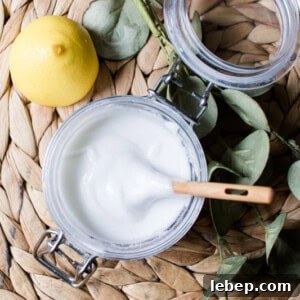 Homemade soft scrub shower cleaner being stirred into a glass container.