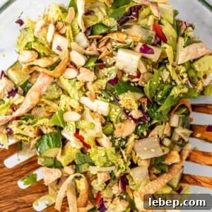 Crispy Asian Chicken Salad with Sesame Ginger Dressing 11 Chopped salad with chicken and almonds in a large bowl.