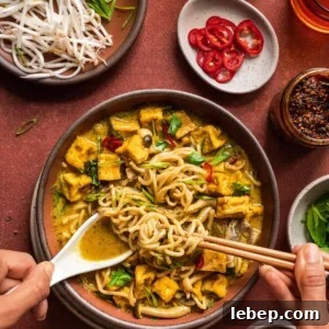 Malaysian curry soup with women's hands digging in with a spoon and chopsticks.