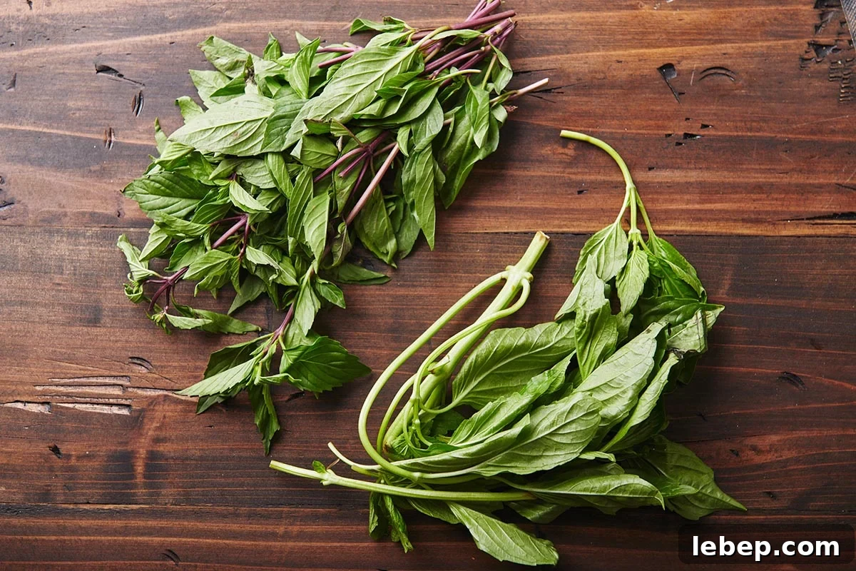 Cooking with Basil: 12 Flavorful Ways to Use Fresh Basil in Meals 3 Fresh Italian and Thai basil on a wooden board.