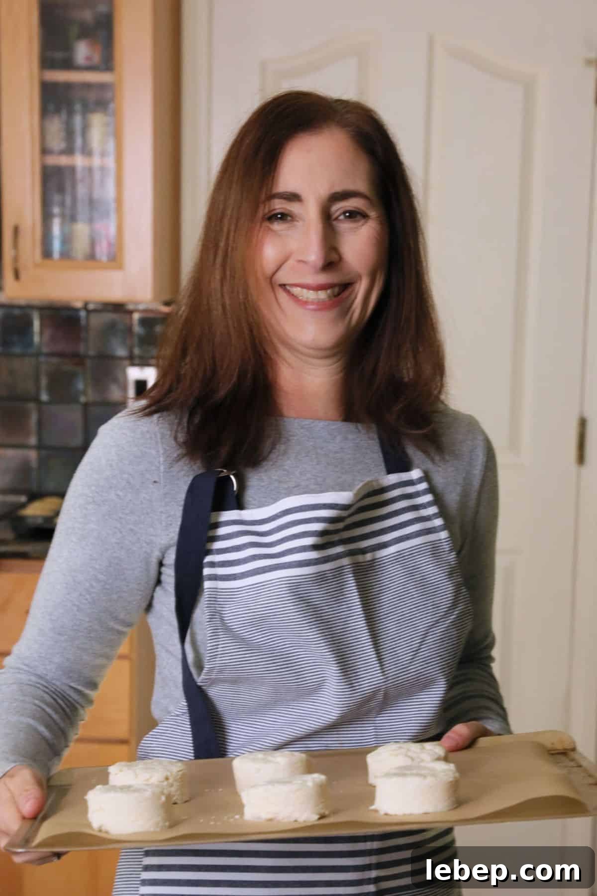 Gluten-Free Apple Fritters: Air Fryer or Classic Fried Recipe 4 Sandi holding a tray of biscuits that are going in the oven to bake.