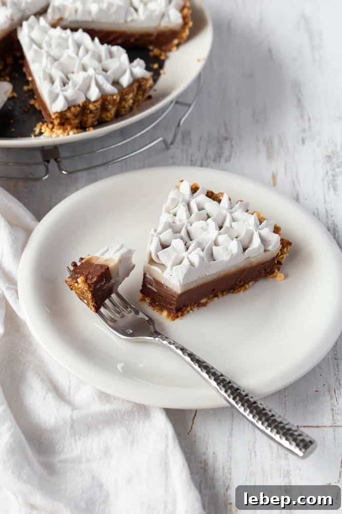 Chocolate Haupia Pie Recipe — Creamy Hawaiian Coconut Dessert 3 A slice of vegan haupia pie on a plate with a fork holding a bite.