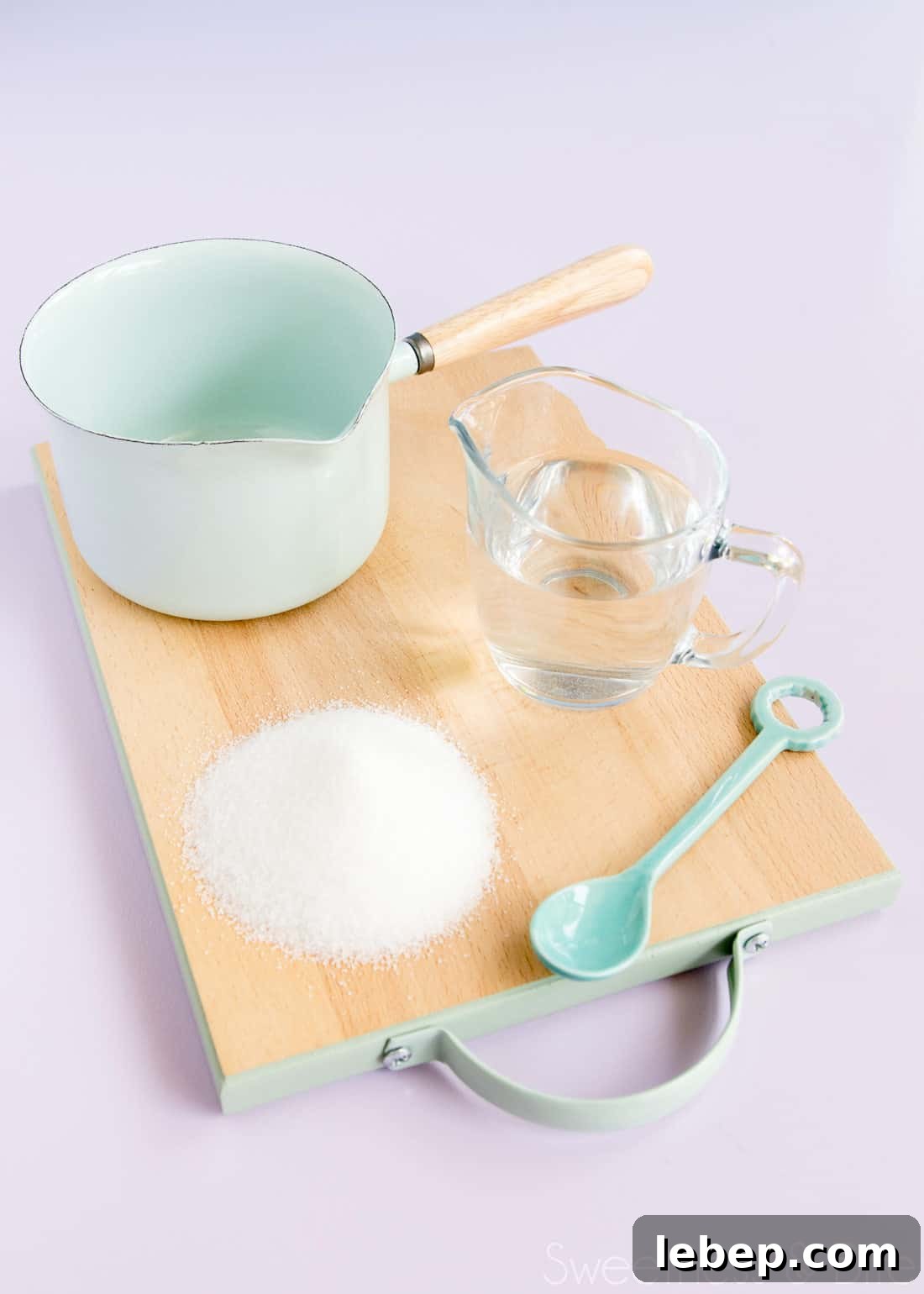 Sugar syrup ingredients and equipment - sugar, water, a small pan and a spoon.