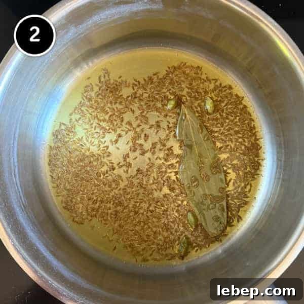 Cumin, bay leaf and cardamom pods frying in ghee. The base for Indian Jeera Rice (Cumin Rice)